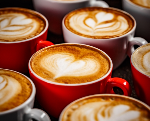 Close up of many cups of cappuccino with latte art on dark background